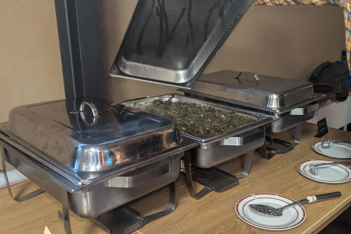 3 Speisewärmer stehen auf dem Tisch, ein Deckel ist angehoben, Man erkennt Grünkohl